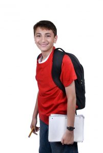 A young boy with a backback and school books. Isolated on white.